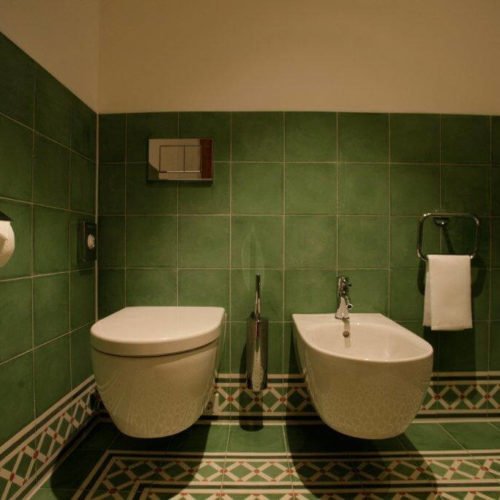 Zementfliesen im Gäste WC verlegt in einem Hotel in Lech am Arlberg | Muster 144, 449AB und Unifliesen in den Farben Elfenbein (M02), Tanne (M26), Grasgrün (M25) und Rot (M12) | Referenznummer: 1948
