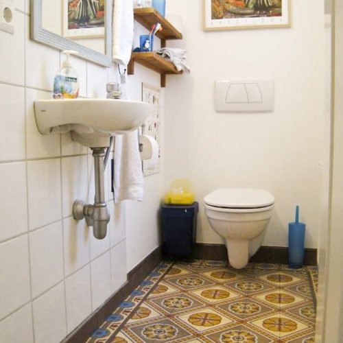 Zementfliesen im Gäste WC verlegt in einem Haus in Lobberich | Muster 252, 484AB und Unifliesen in den Farben Mahagoni (M14), Senf (M06), Elfenbein (M02), Himmelblau (M20), Zimt (M35) und Bordeaux (M13) | Referenznummer: 5131