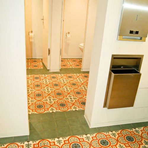 Fliesen im Gäste WC verlegt in einem Restaurant (München) | Muster 247 und Unifliesen in den Farben Schwarzoliv (M53), Gelb (M05), Rot (M12), Schwarz (M34), Weiß (M01) und Blau (M19) | Referenznummer: 5736 / S404