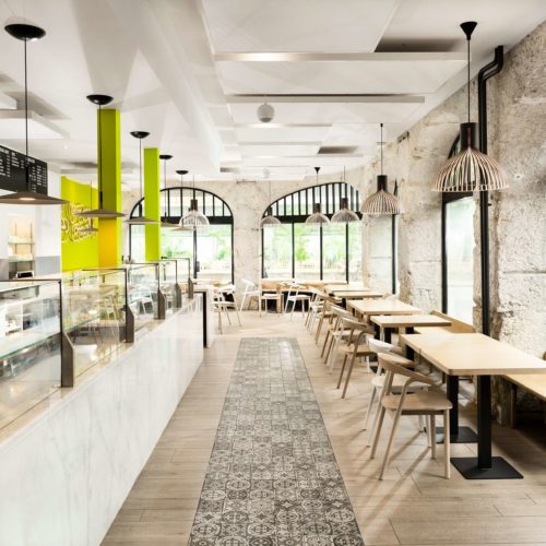 Zementfliesen verlegt in einem Restaurant zwischen Tresen und Sitzplätzen | Muster 1059, 1060 und 1061 in den Farben Stein (M30) und Schwarz (M34) | Referenznummer: 2209 / S2300