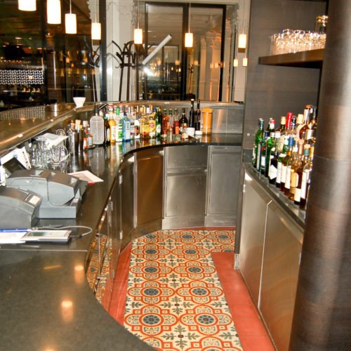 Zementfliesen in einer Bar verlegt in München | Muster 247 und Unifliesen in den Farben Schwarzoliv (M53), Gelb (M05), Rot (M12), Schwarz (M34), Weiß (M01) und Blau (M19) | Referenznummer: S404
